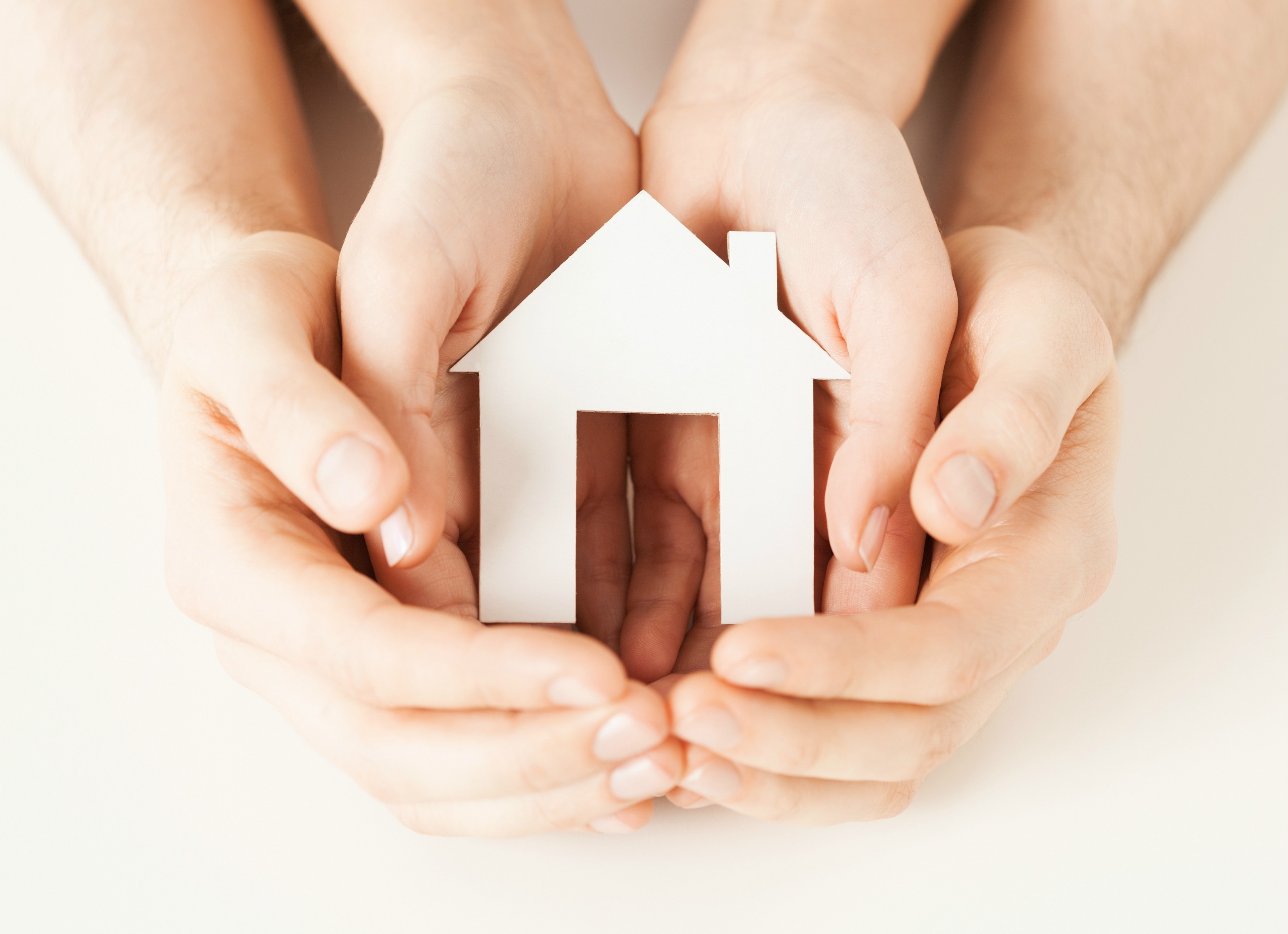 pisture of man and woman hands holding paper house