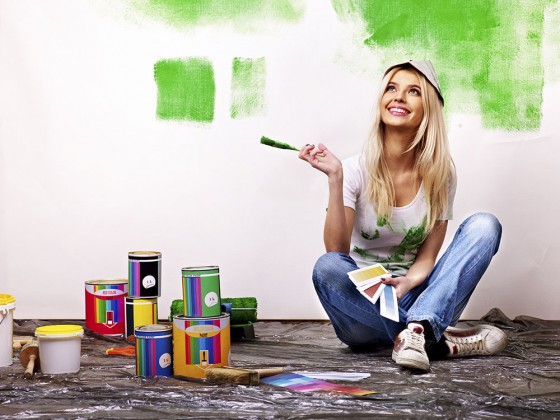 Beautiful,happy,blond woman painting her condos walls bright green.